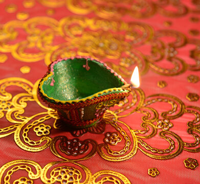 An illuminated, Diwali lamp against glittering  decorative background. Hindu festive objects and elements.