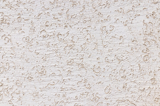Full-frame close-up captures a textured white wall with irregular squiggly patterns and indentations.
