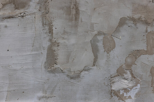 Full-frame overhead view of a gray textured concrete surface. Visible signs of construction and repair with uneven patches and variations in application highlight its industrial character.