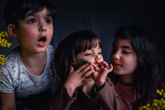 Three young sisters with amazed and curious expressions playing together