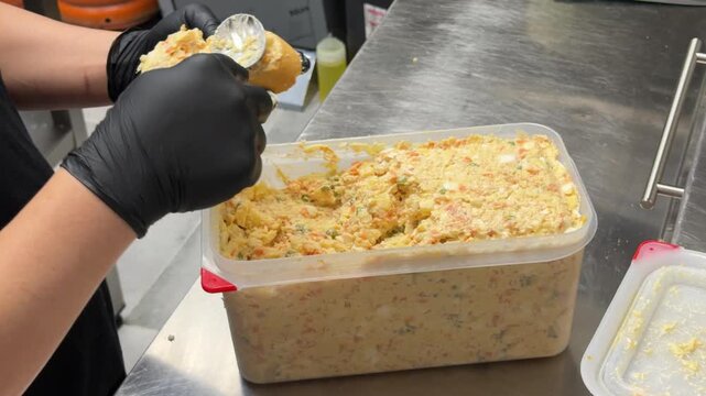 Chef spreading russian salad on bread for pintxos in kitchen