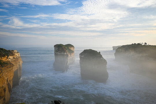 beautiful photo of a twelve apostles two beautiful cliffs standing strong in the ocean in cloudy weather