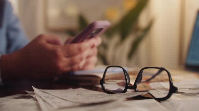 Accountant hands using phone typing, calculate taxes, budget smartphone on background stack of documents, invoices, expenses. High quality 4k footage