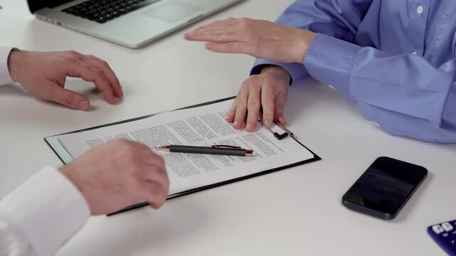 Signing Documents and Receiving Cash. People signing documents at office table with paperwork, pen, laptop, and smartphone during contract agreement and cash payment discussion in a professional busin