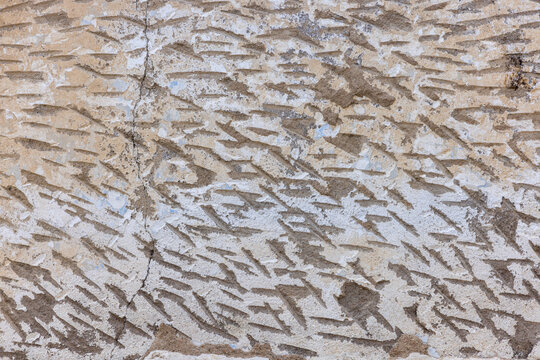 Close-up view of a textured concrete wall featuring shallow linear indentations preparing wall for stucco application,