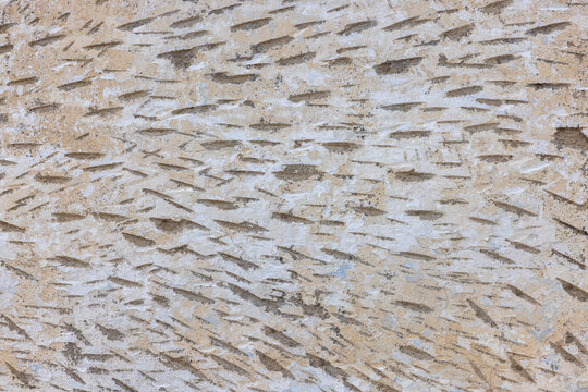 Close-up view of a textured wall surface featuring a rough finish with angled indentations for stucco adhesion.