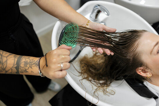 Hairdresser detangling wet hair at a salon shampoo basin