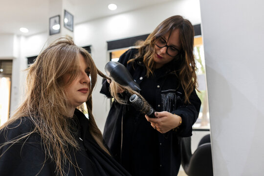 Hairdresser blow drying a client's hair in a salon