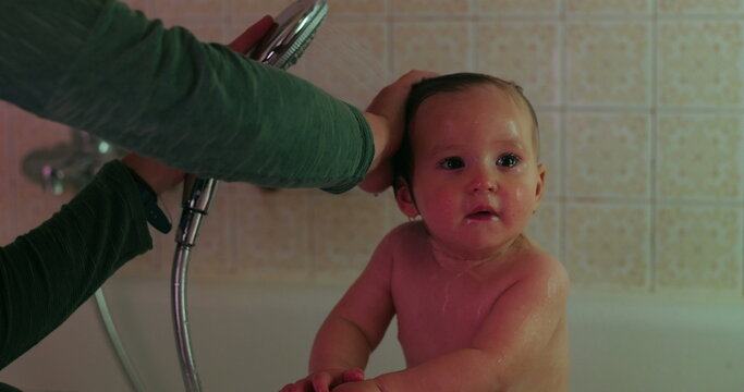 Caregiver showers toddler&rsquo;s wet hair in home bathtub as delighted child giggles, highlighting gentle hygiene, playful caregiving, positive routines and family connection