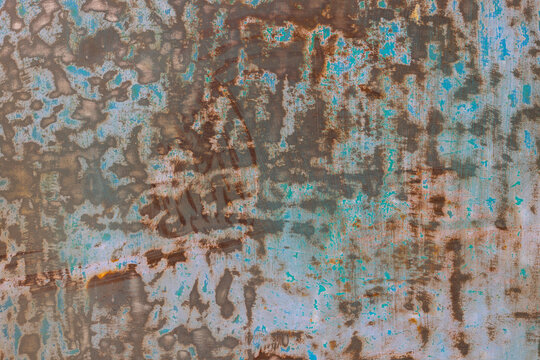 Close-up view of a weathered metal surface displaying peeling light blue and turquoise paint over a rusty brown base. The rough texture indicates age and exposure to elements, with no people present.