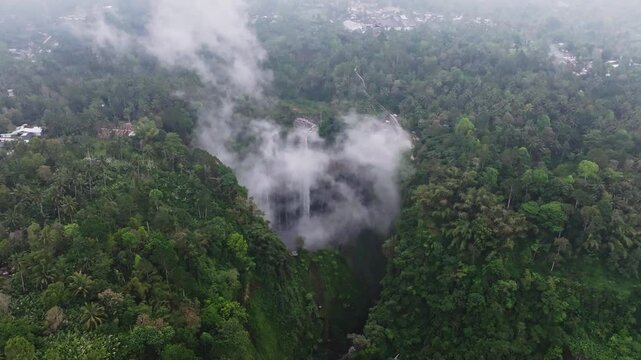 Wide Aerial Drone Orbit Around Tumpak Sewu Waterfall Surrounded by Lush Tropical Forest on an Overcast Day in East Java, Indonesia