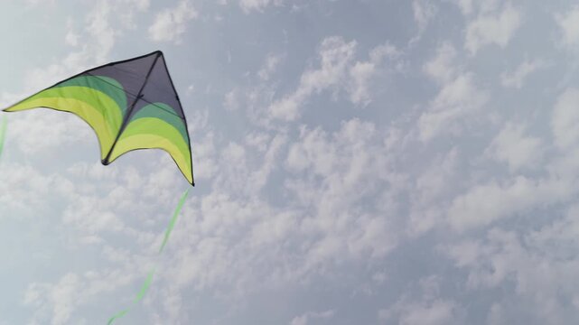 A kite in a blue sky with white clouds slow motion view from below