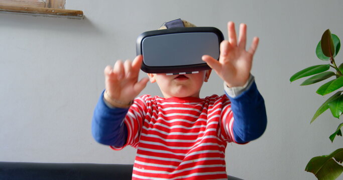 Front view of Caucasian boy using virtual reality headset in living room at home
