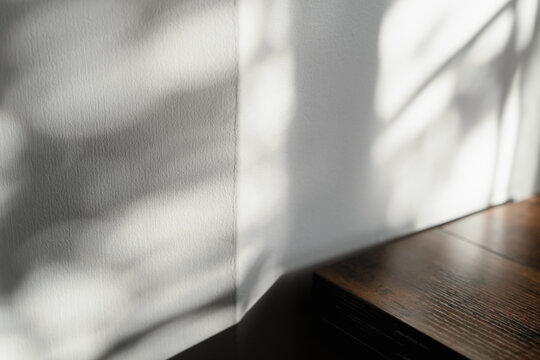 Background shadow on white grey cement wall with soft window light, Concrete texture and dark brown wooden table, Empty interior studio for Spring product display, Summer banner, Minimalist design