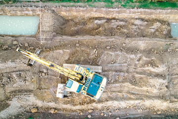 Aerial top view of yellow hydraulic excavator on dirt The Concept of construction and development © VicVaz