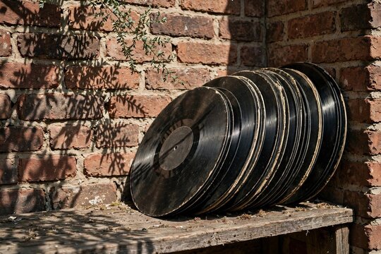 Stack of old vinyl records leaning against a brick wall