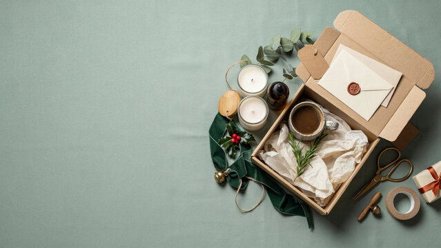 Premium Holiday Gift Set Packaging with Candle, Speckled Ceramic Mug, Amber Glass Bottle, Kraft Gift Box and Gold Velvet Ribbon on Textured Sage Green Background