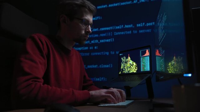 Concentrated male coder in glasses works at a dark office desk, surrounded by screens filled with programming code and graph, absorbed in solving a complex AI or data science problem late at night.