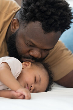 African American father kissing on head of newborn baby infant with kidly and love, adorable smiling mixed race baby, fatherhood moments, love and parenting care at home