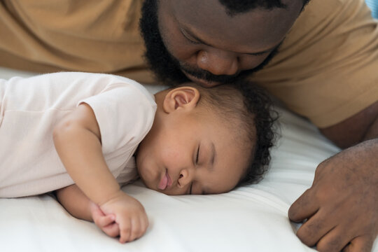 African American father kissing on head of newborn baby infant with kidly and love, adorable smiling mixed race baby, fatherhood moments, love and parenting care at home