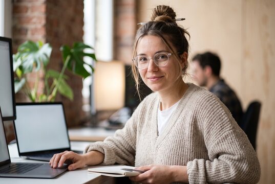 Jeune femme fran&ccedil;aise souriante &agrave; lunettes travaillant sur ordinateur portable dans un bureau loft, startup, t&eacute;l&eacute;travail et cr&eacute;ativit&eacute;