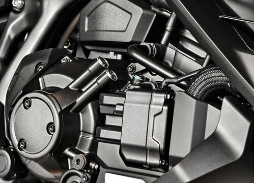 Motorcycle engine pump cover with bolts and textured cast metal surfaces showing hoses and hardware
