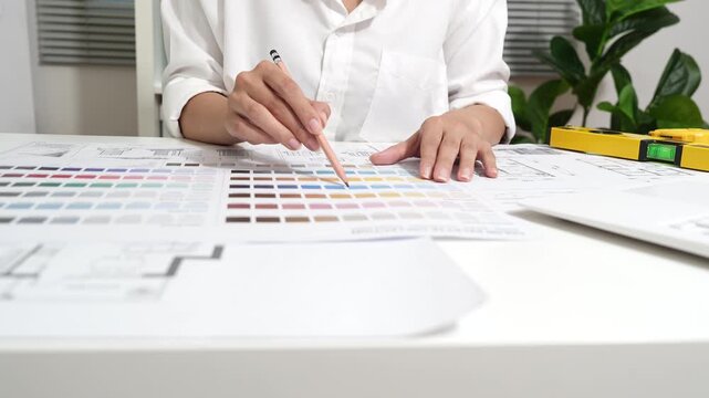 Architect reviewing residential blueprints with a pen and measuring tape, planning house design and construction in a professional workspace with warm natural light.