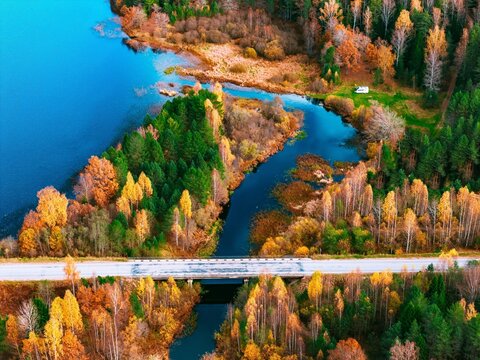 Colorful autumn trees framing a winding river and bridge in a serene landscape