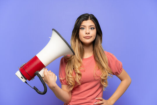 Young Russian girl isolated on blue background holding a megaphone with stressed expression