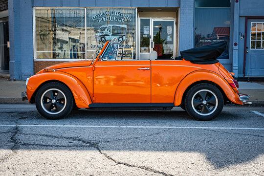 Orange Volkswagen Super Beetle Convertible parked on a street