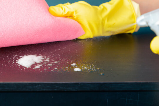 obsessive compulsive disorder cleaning sprayed liquid droplets on dark table surface background gloved hand wiping wet stains with pink cloth with copy space for banner ocd, mental health, psychology