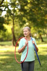 Senior woman with hula hoops in park, space for text © New Africa