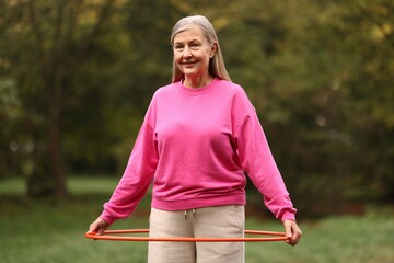 Senior woman exercising with hula hoop outdoors © New Africa