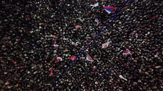 Beograd, Serbia - 22 October 2026: Aerial view of a massive crowd of protesters gathered at Slavija Square, with many people holding flags and banners.