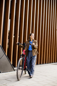 Korean woman joyfully riding her electric bicycle near modern architecture