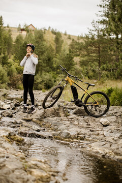 Mountain biker pauses beside a yellow bicycle on rocky trail
