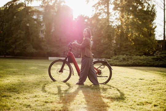 Korean woman walks her e bike through the golden evening light