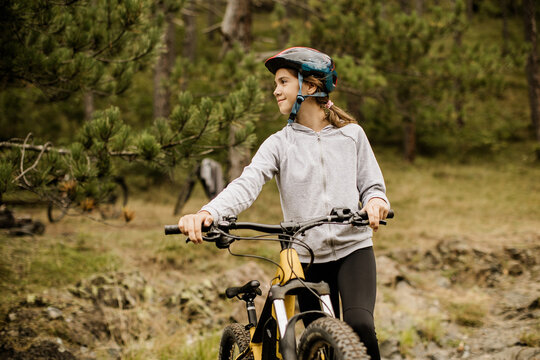 Young cyclist pauses on a forest trail in the afternoon
