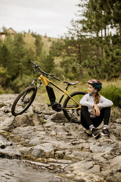 Rider pauses beside an electric mountain bike on a rocky trail
