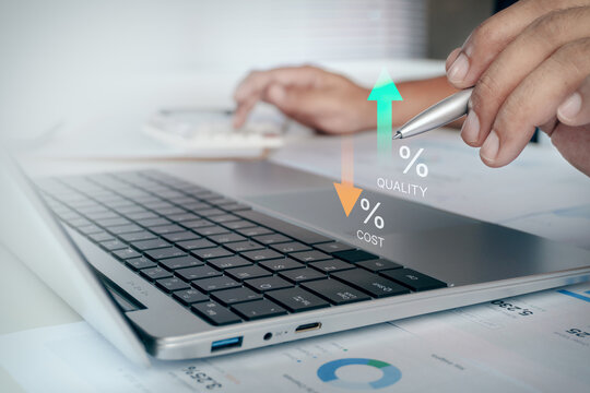 Businessman pointing pen on digital interface at laptop screen with icon overlay showing high quality upward arrow and low cost downward arrow, concept of cost reduction and quality improvement.