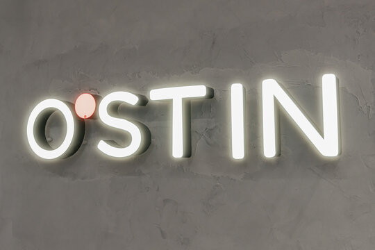 Belgrad, Serbia, 28 09 2026: O'STIN clothing brand illuminated logo sign on a gray textured wall close up
