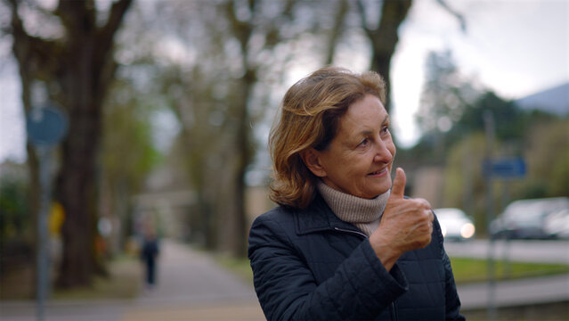 Cheerful Caucasian senior woman giving a thumbs up in the park, approval, positivity and zest for life