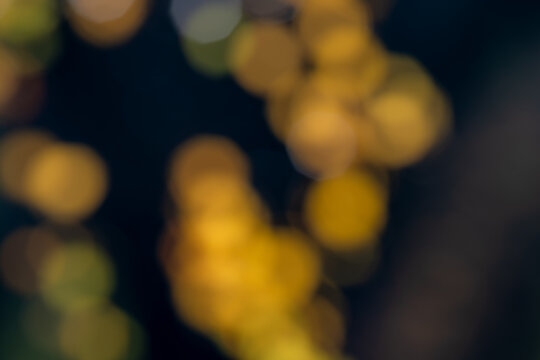 Abstract autumn background with blurred golden yellow birch leaves, warm amber bokeh lights and deep blue tones, creating a soft seasonal nature backdrop with copy space.