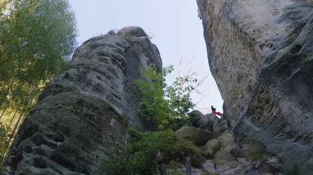 A slow gimbal swirl facing upwards towards dramatic sandstone formations, is revealing two rock climbers that are unrecognizable at the Bohemian Paradise area. a 4K video clip.