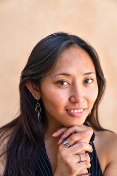 headshot portrait of woman hands on chin looking at camera demure