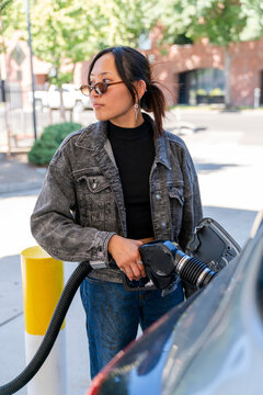 portrait woman at gasoline pump pumping gas nozzle