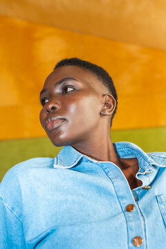 Woman Looks to the Side Wearing a Denim Shirt Against a Colored Wall