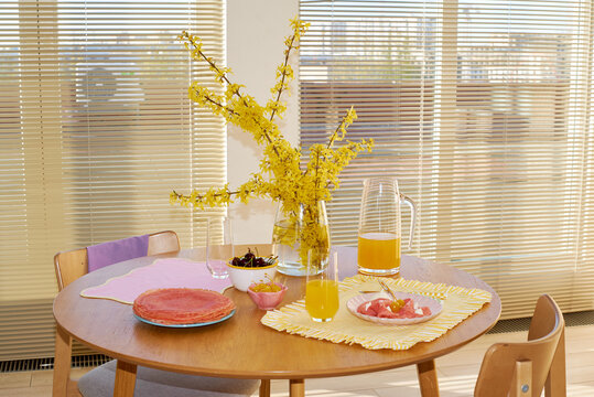 A round wooden table is set for breakfast
