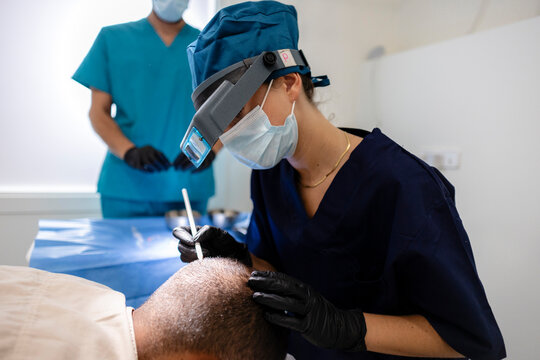 Surgeon performing hair transplant procedure using capillary injector