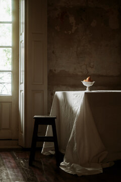 Empty Room With a Table, Stool, and Bowl of Fruit in Soft Light